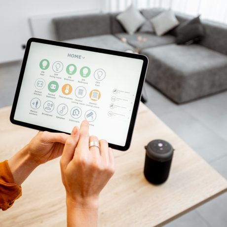 Woman controlling smart devices with a digital tablet at home Young woman controlling home with a digital touch screen panel. Concept of a smart home and mobile application for managing smart devices at home
